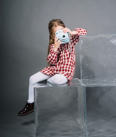 niña con cámara de fotos instantánea